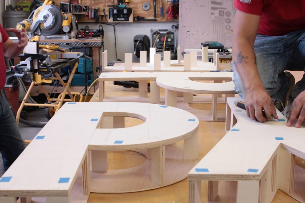 Shaped wooden letter components and curved sections on a workbench.