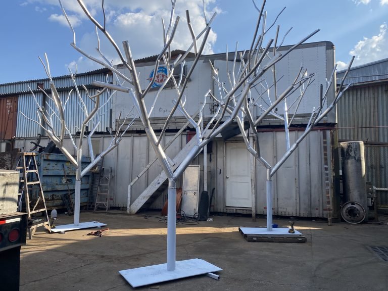 White branching scenic structures on rectangular bases in an outdoor work area.