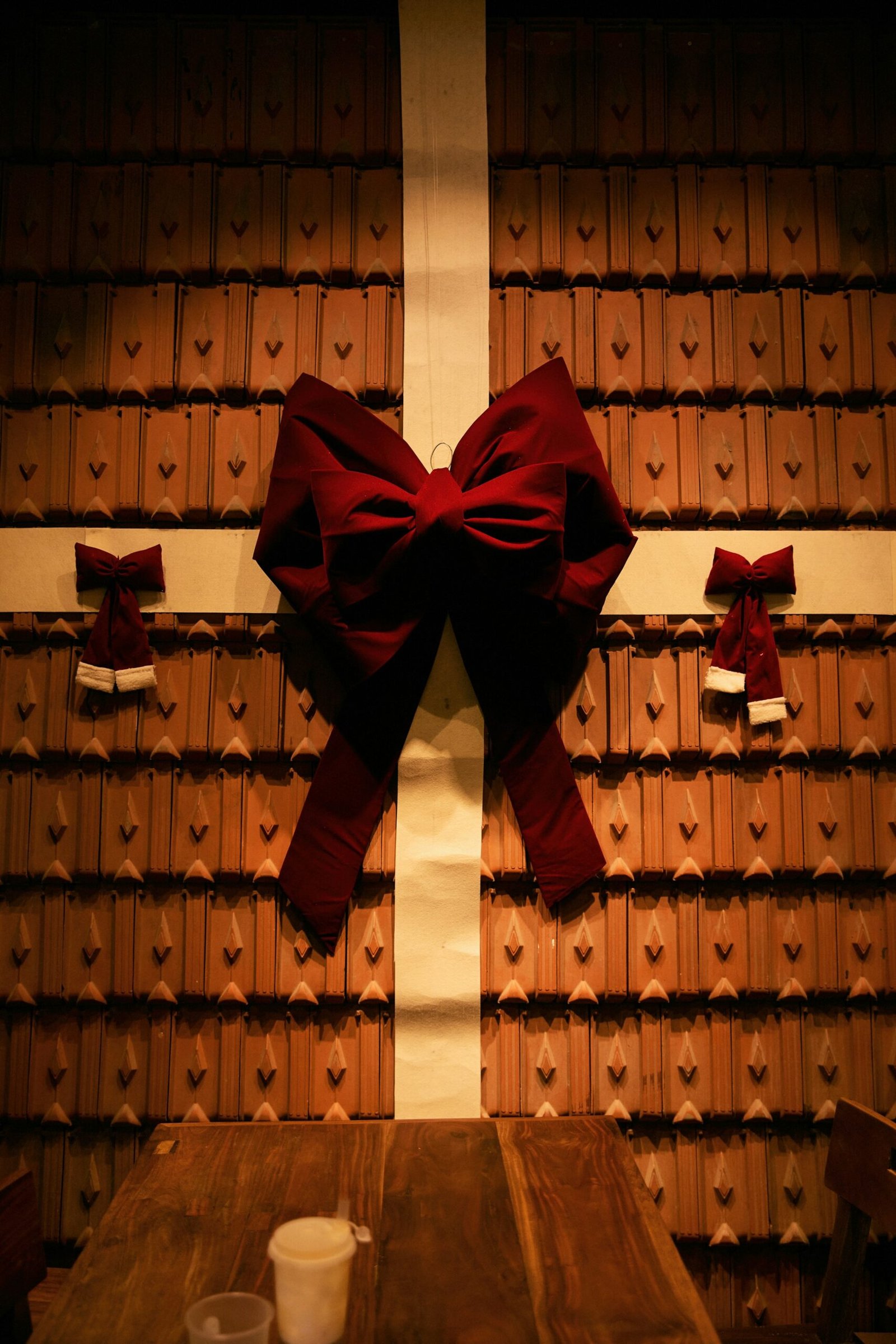 Large red Christmas bow centered on a tiled interior wall