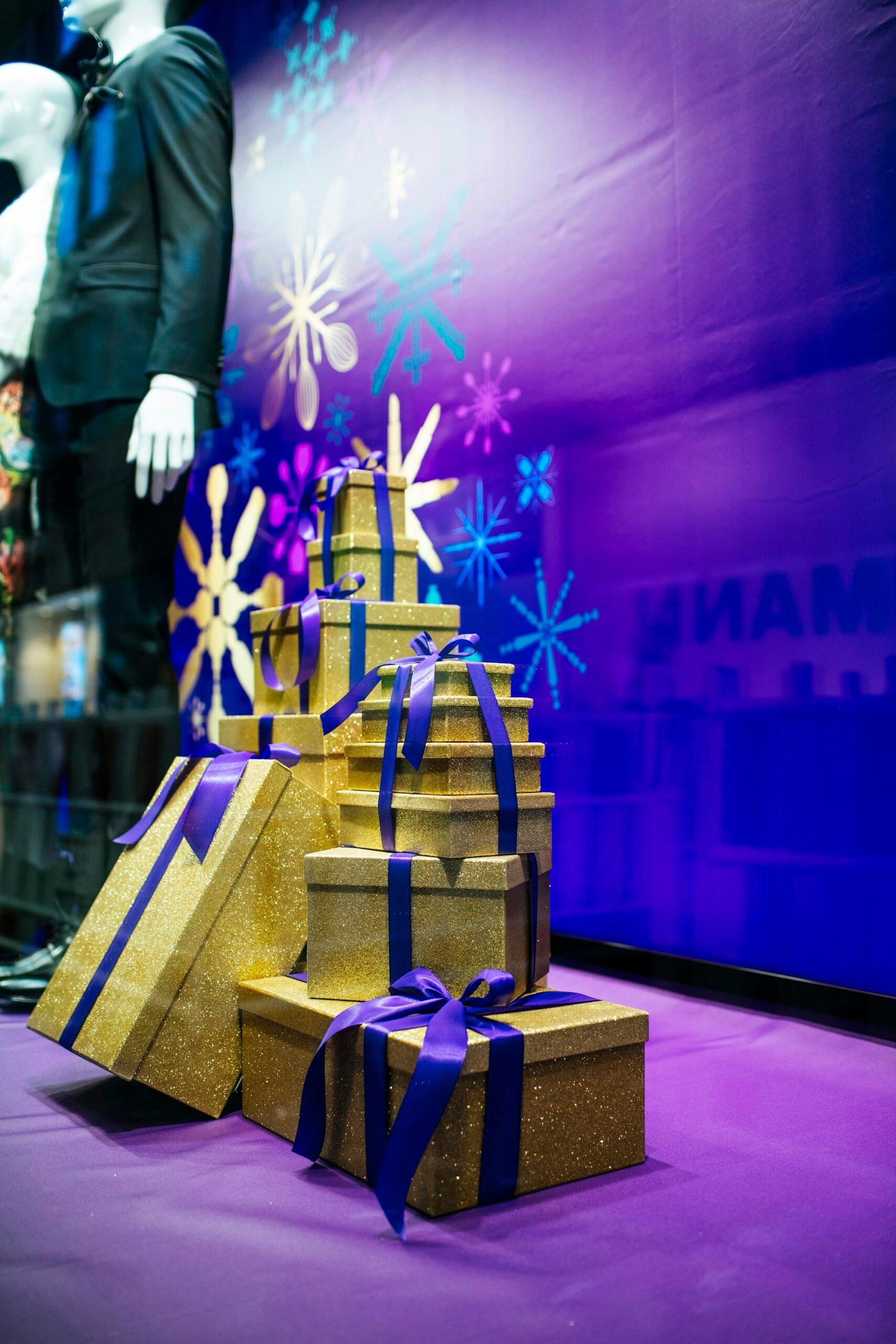 Gold gift boxes with purple ribbons arranged in a Christmas shop window